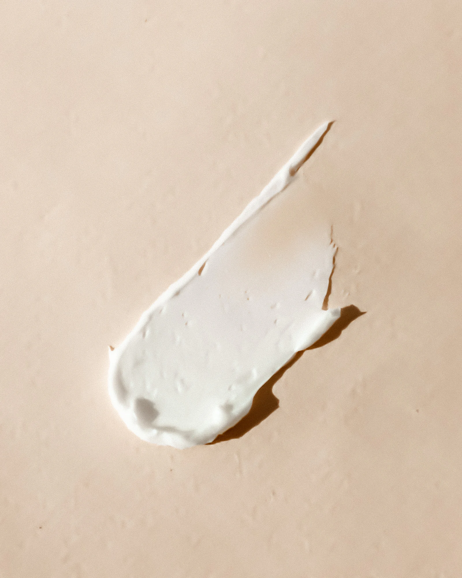 A single smear of white cream on a warm beige surface