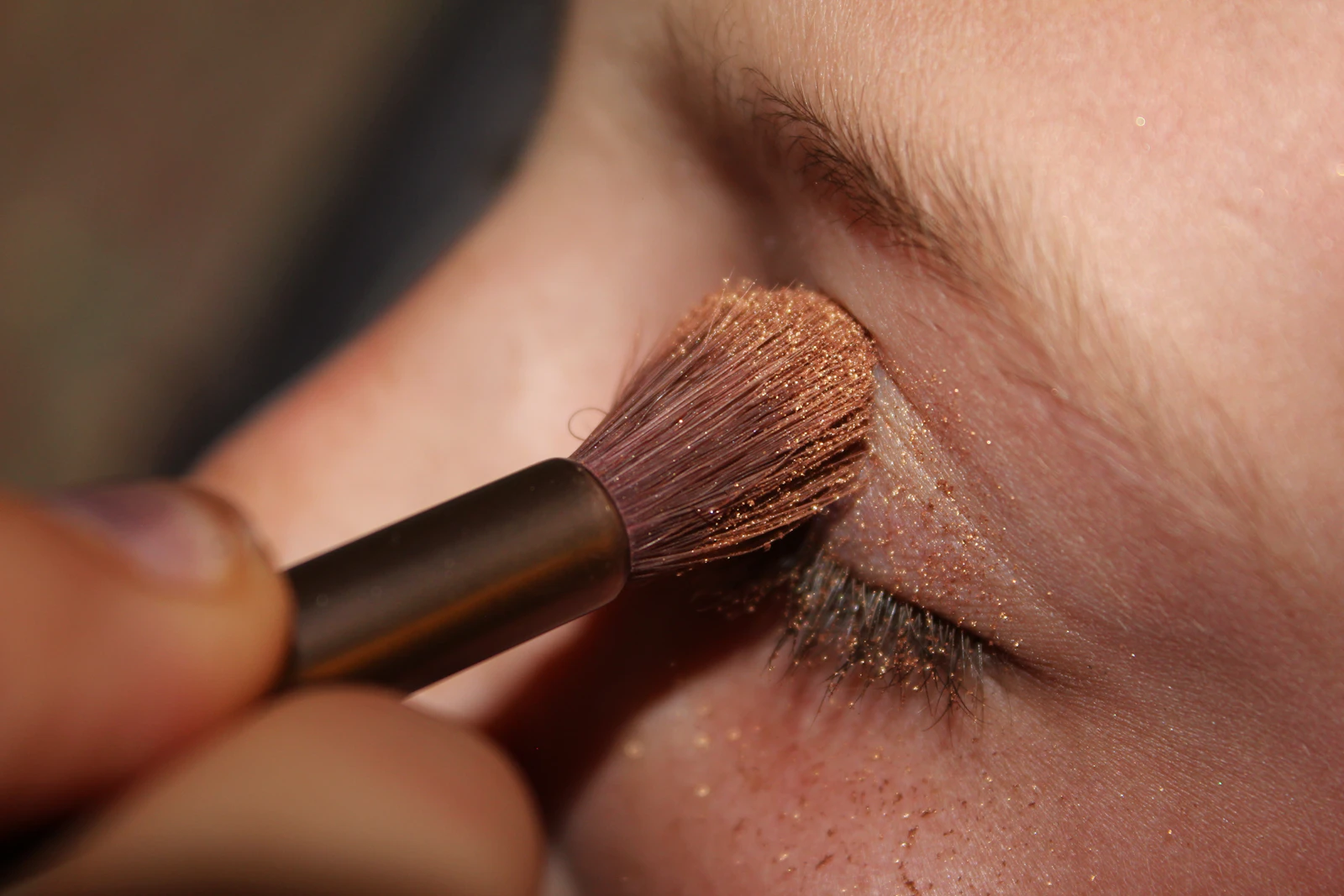 A soft brush blending warm shadow across a freckled eyelid