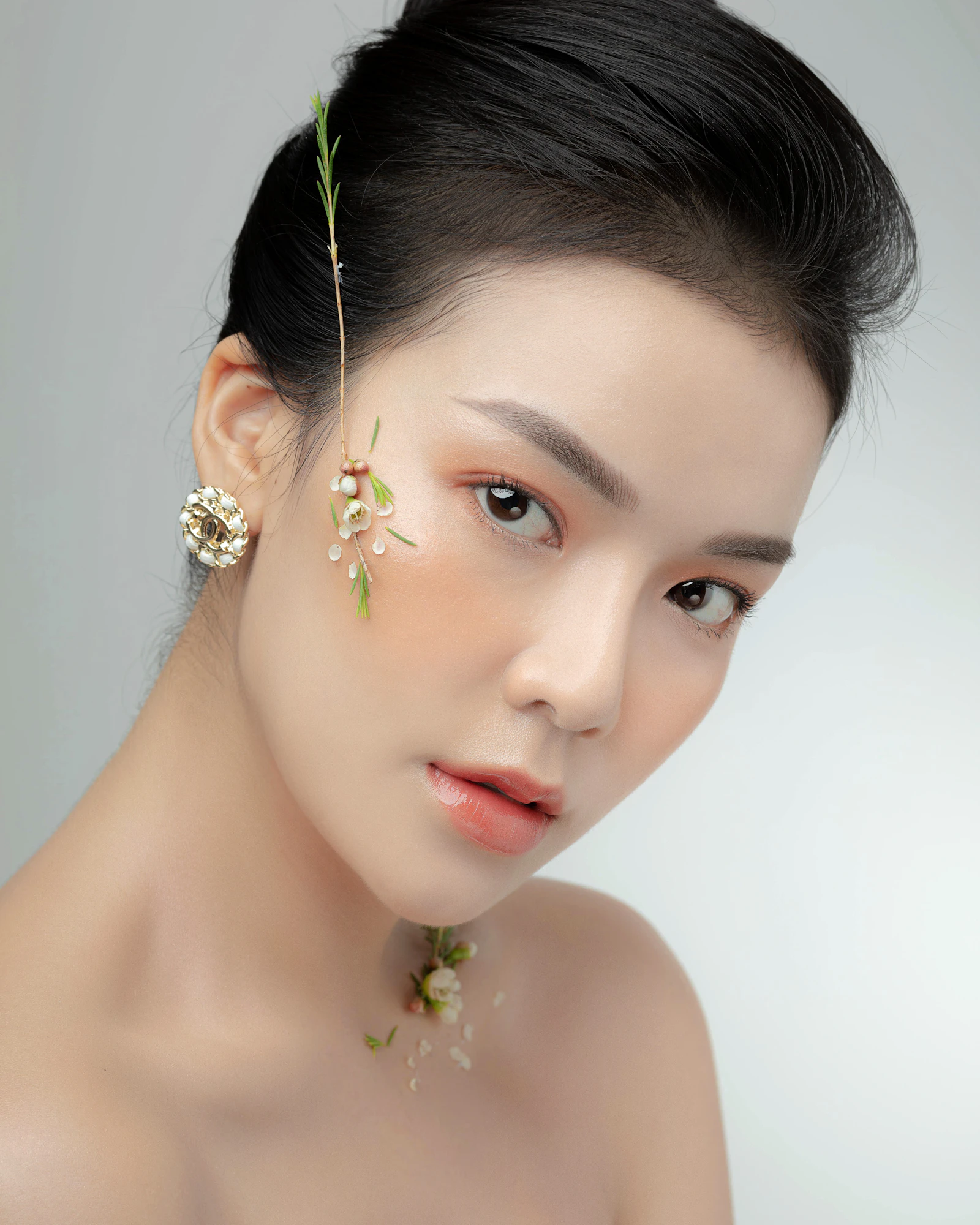 Woman with an even, fresh complexion and tiny white flowers tucked along her cheek