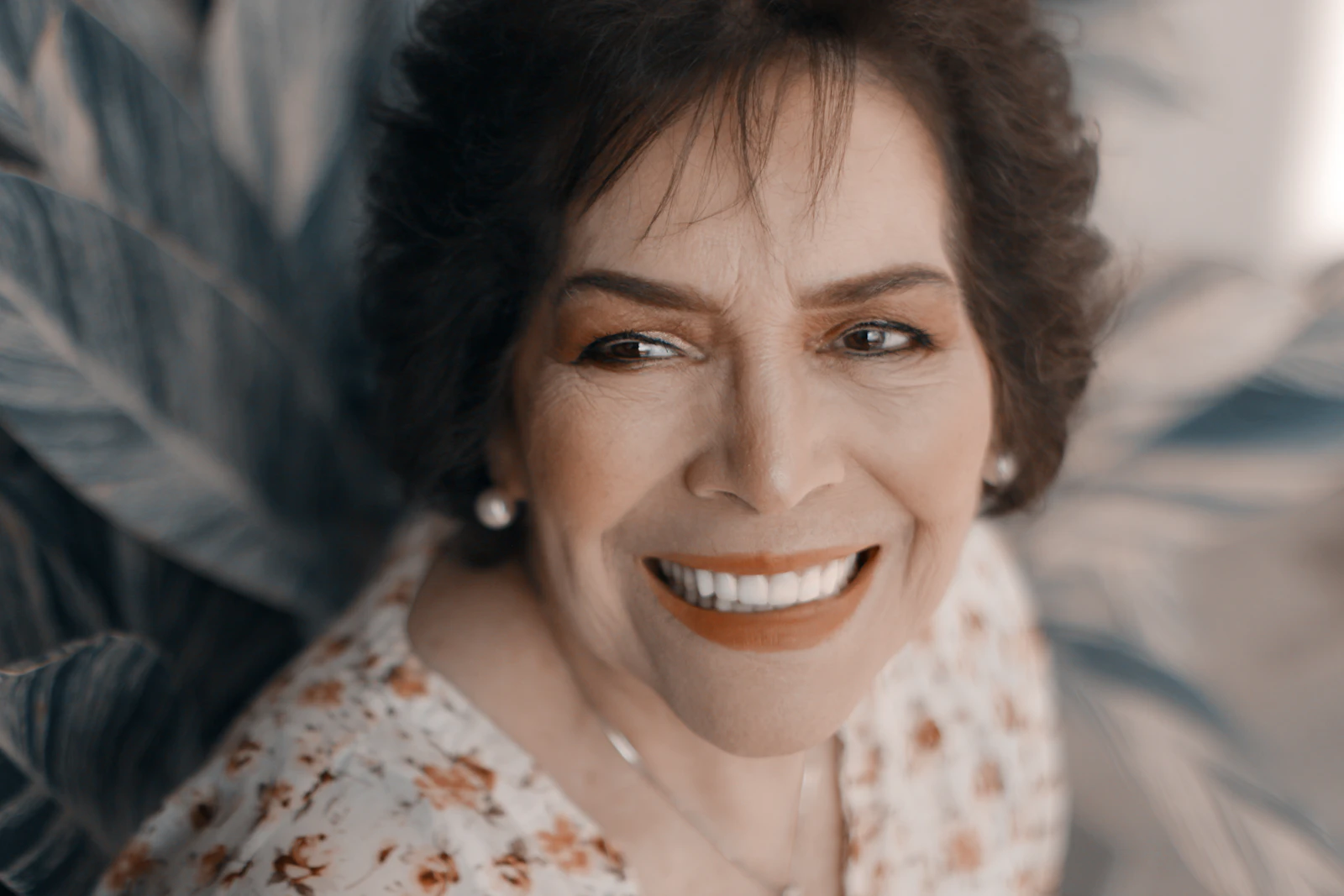 Smiling woman with short dark hair and a soft coral lip